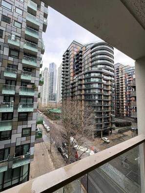 Un edificio residencial alto con múltiples balcones, un diseño arquitectónico curvo y vistas a una calle con coches estacionados.
