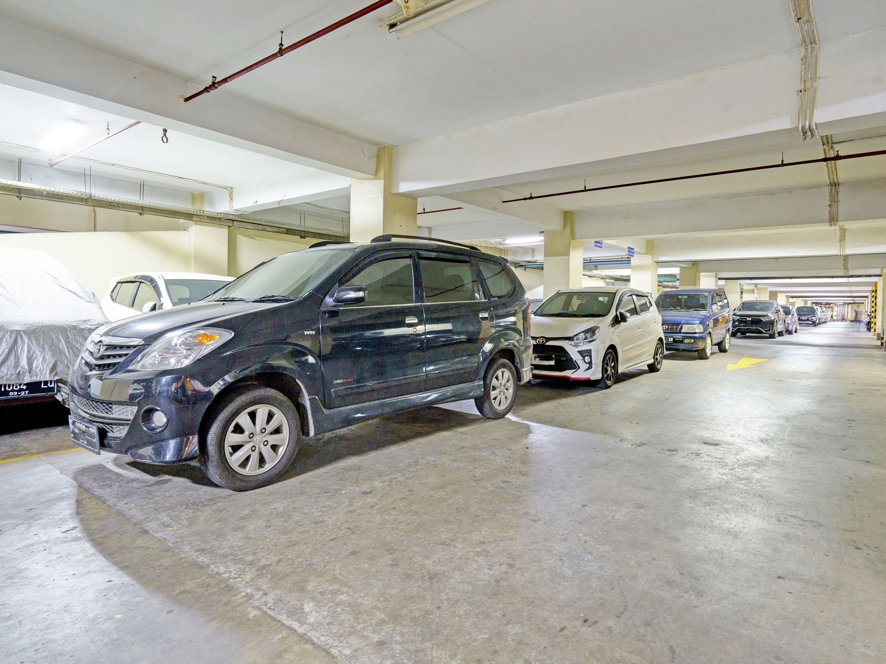 Un parking à plusieurs niveaux où sont stationnées plusieurs voitures.