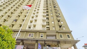 A high-rise building with multiple balconies and a flag.