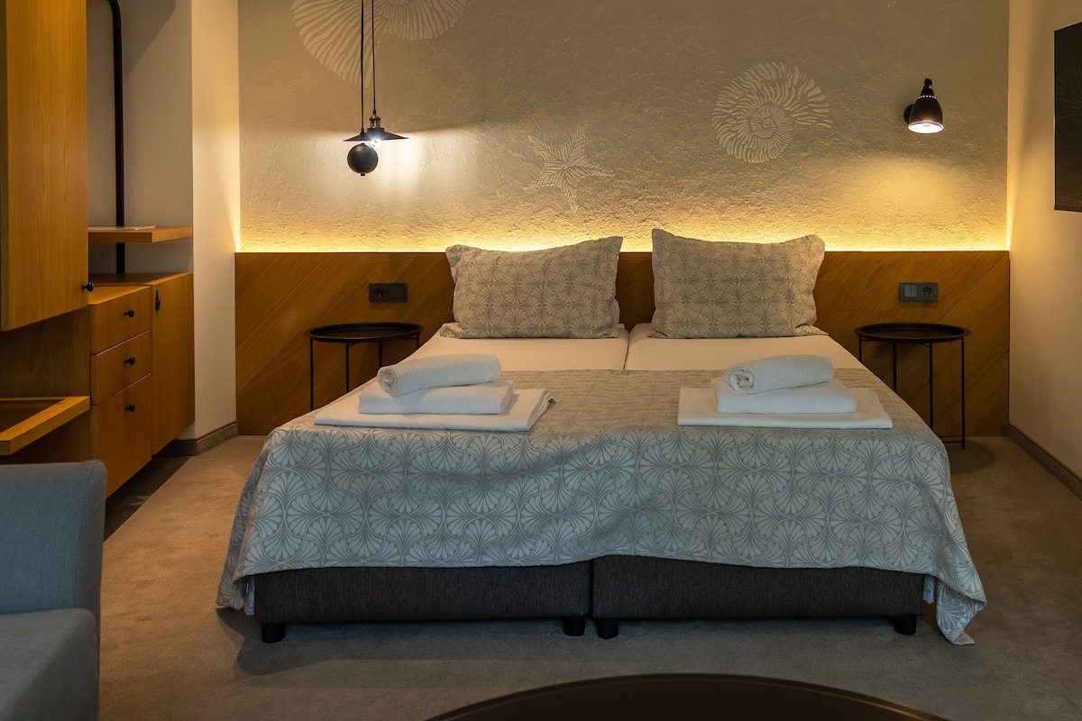 A neatly arranged bedroom with a bed, two bedside tables, a nightstand, and a wardrobe.
