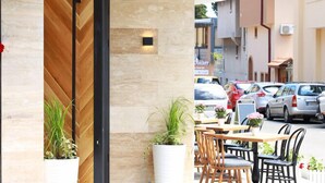 Una zona de recepción con puerta de madera, plantas en macetas y asientos exteriores.