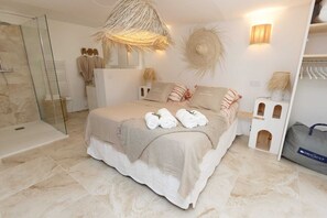 Ein modernes Schlafzimmer mit einem großen Bett, einer Duschkabine aus Glas und einer kleinen Ablage.