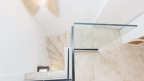 A modern interior with a glass staircase, marble walls, and a hanging light fixture. - CASA Farniente Appart Cocooning Provence Verte (Montfort-sur-Argens)