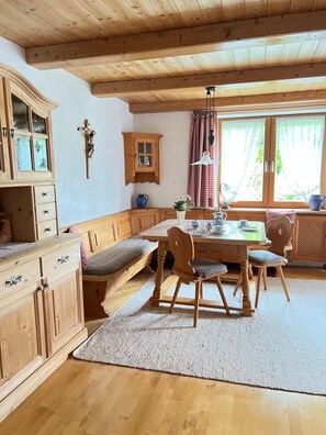 A wooden interior with a dining table, chairs, a bench, and a cabinet.