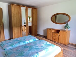A bedroom with a bed, a wardrobe, a dresser, and a mirror.
