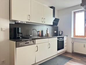 A modern kitchen with white cabinets, a black countertop, and a window providing natural light.
