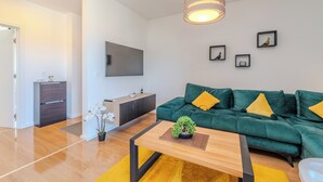 A modern living room with a green sofa, a wooden coffee table, and a mounted flat-screen TV. - Apartment Babic (Vir)