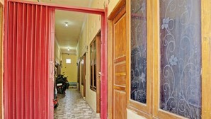 A hallway with a red door, a tiled floor, and a motorcycle parked in the background. - OYO Life  92936 Kost Teteh Erni Karawang (Karawang)