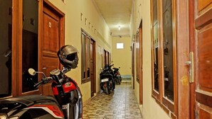 A narrow hallway with wooden doors and a tiled floor. - OYO Life  92936 Kost Teteh Erni Karawang (Karawang)