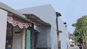 A narrow street with a building featuring a corrugated metal roof and a partially open door. - OYO Life  92936 Kost Teteh Erni Karawang (Karawang)