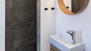 A modern bathroom with a large mirror, a shower, and a vanity with a sink. - Room Odin (Dubrovnik)