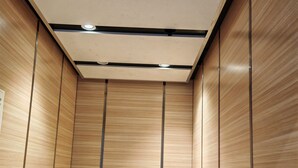 A modern elevator interior with wooden panel walls and metal handrails. - Pangkor Pop Ash Hotel (Pangkor Island)