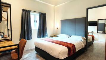 Quarto de hotel com uma cama, uma escrivaninha e uma cadeira.
