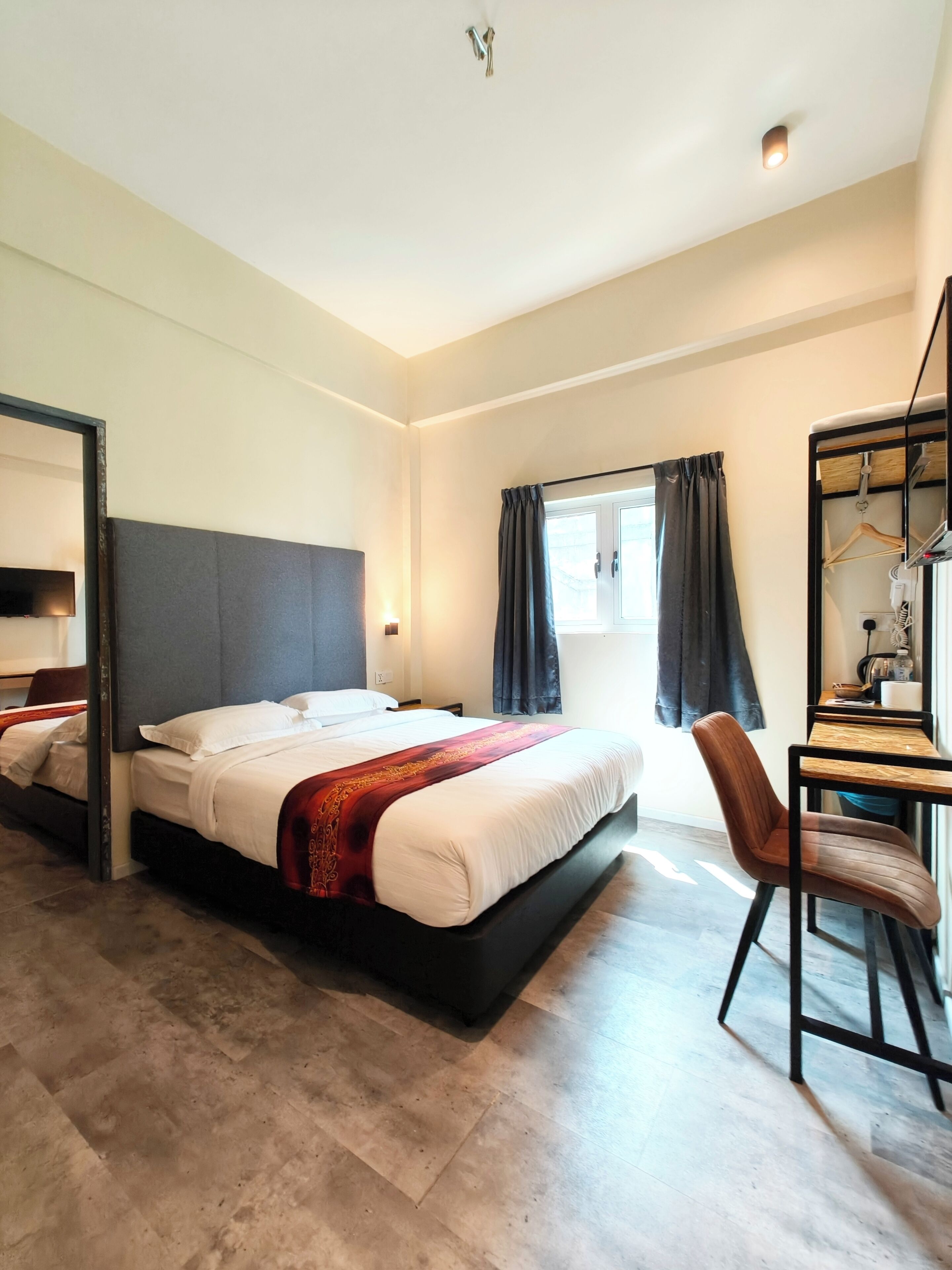 A modern hotel room with a large bed, a desk, and a mirror.