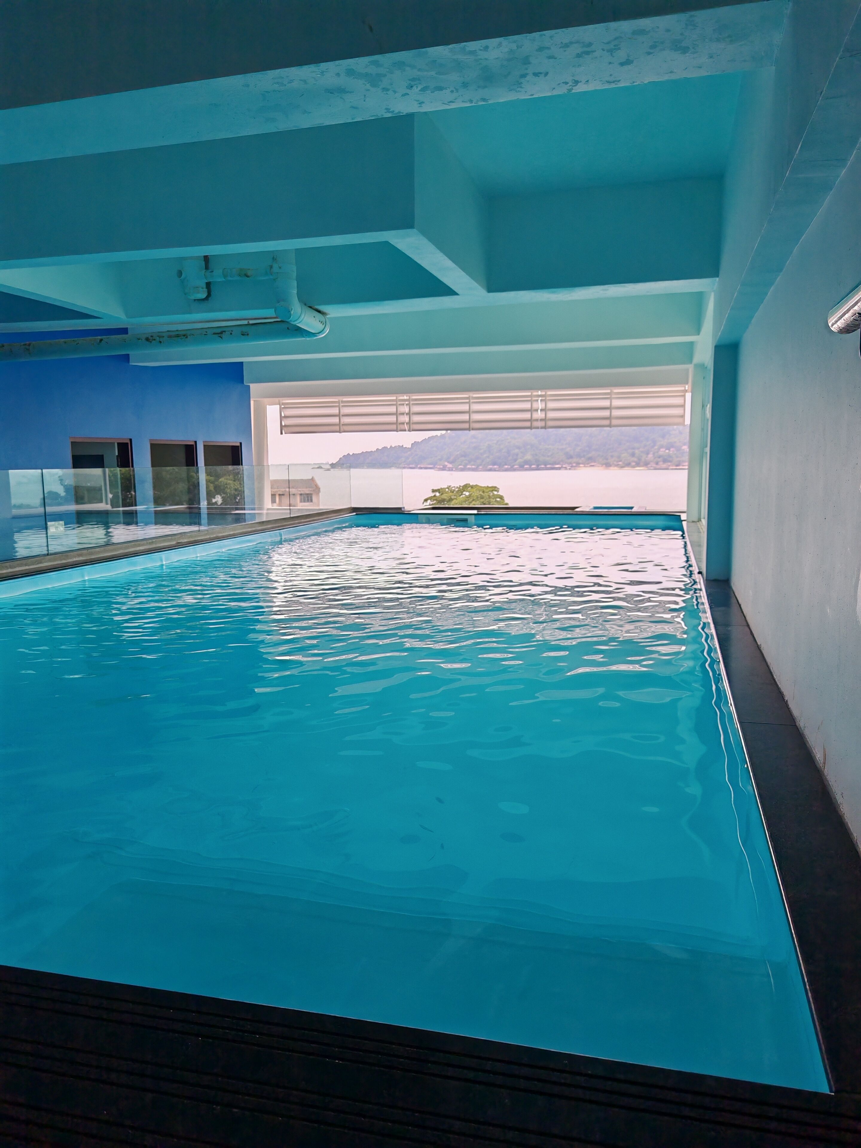 An indoor swimming pool with clear water, a view of the outdoors through large windows, and a modern architectural design.