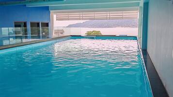 Una piscina interior con agua cristalina, vistas al exterior a través de amplios ventanales y un diseño arquitectónico moderno.