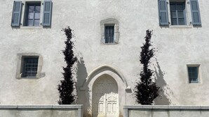 A building with a central arched doorway, flanked by two symmetrical windows with shutters, and a smaller window above.