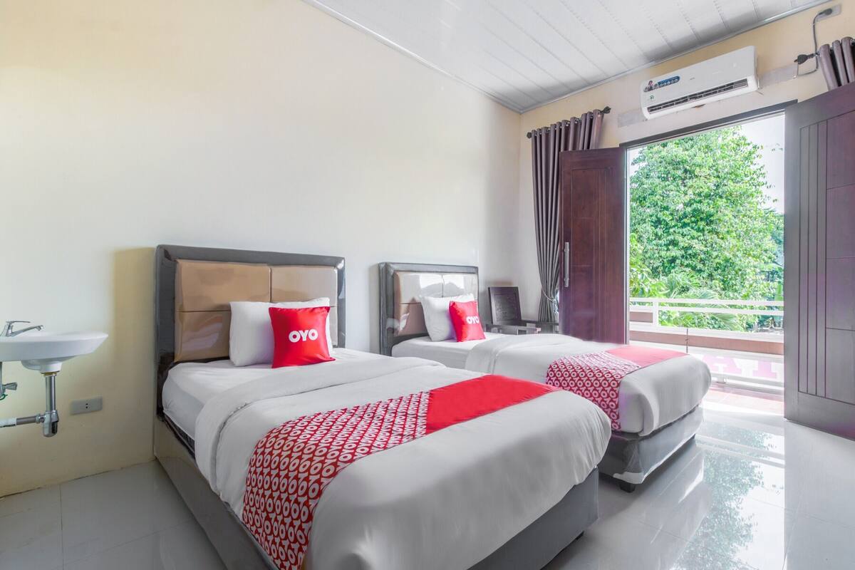 Habitación de hotel con dos camas, un lavabo y un equipo de aire acondicionado.