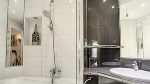 A modern bathroom with a bathtub, a shower, and a vanity with a mirror.