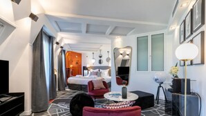 A modern hotel room with a large bed, a red armchair, a round coffee table, and a globe on a tripod. - Sublim by Sweet Inn Paris (Paris)