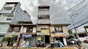 Edifici de diverses plantes amb una botiga a la planta baixa anomenada "MALUHA ARTELLE" i un cartell que diu "KID'S PARTY".