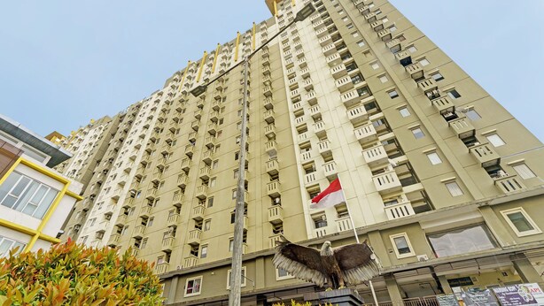 A high-rise residential building with multiple balconies and a flag. - OYO Life 92993 Apartement Gateway Cicadas By Mgm Property (Bandung)