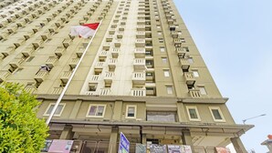 A high-rise building with multiple balconies and a flag. - OYO Life 92993 Apartement Gateway Cicadas By Mgm Property (Bandung)