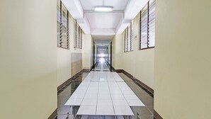 A long, narrow hallway with tiled floors and walls, flanked by windows with blinds. - OYO Life 92993 Apartement Gateway Cicadas By Mgm Property (Bandung)