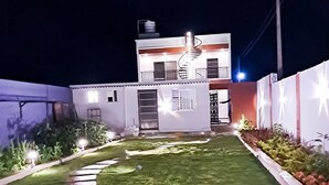 Una casa de dos pisos con una escalera en espiral, un pequeño porche delantero y un césped bien cuidado con un sendero de piedra.