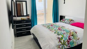 Quarto com cama, penteadeira, espelho e janela com cortinas.