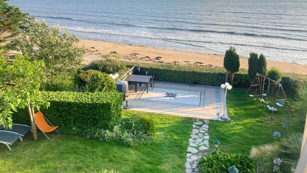 Un patio con un felpudo en forma de estrella, un conjunto de columpios y vista a la playa.