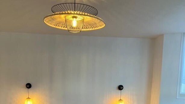 A room with a bed, two bedside lamps, a table, and a chair.