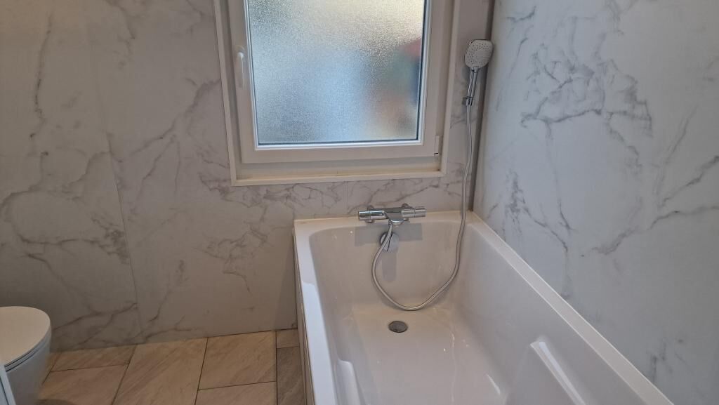Une salle de bain avec une baignoire, des toilettes et une fenêtre.