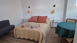 A bedroom with a bed, a small table, a chair, and a sofa.