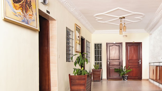A spacious hallway with a tiled floor, wooden doors, and potted plants. - Residence Hotel Edouard (Abidjan)
