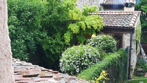 A traditional building with a tiled roof, surrounded by lush greenery and a stone wall.