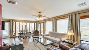 A spacious living room with a ceiling fan, a sofa, a coffee table, and a dining area with chairs and a table.