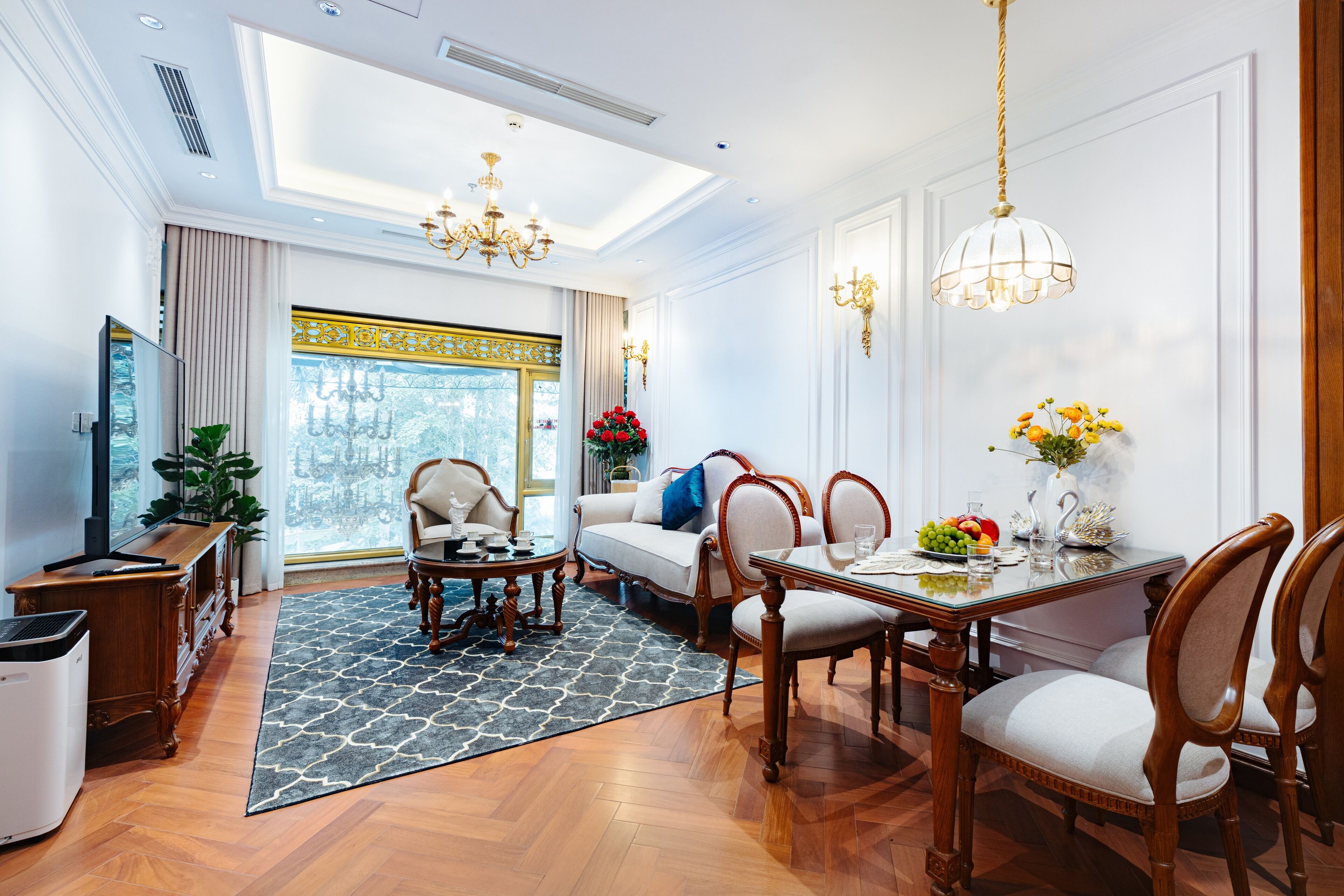 Un salon spacieux comprenant un canapé, une table à manger et des chaises. Une grande fenêtre offre une vue sur les arbres.