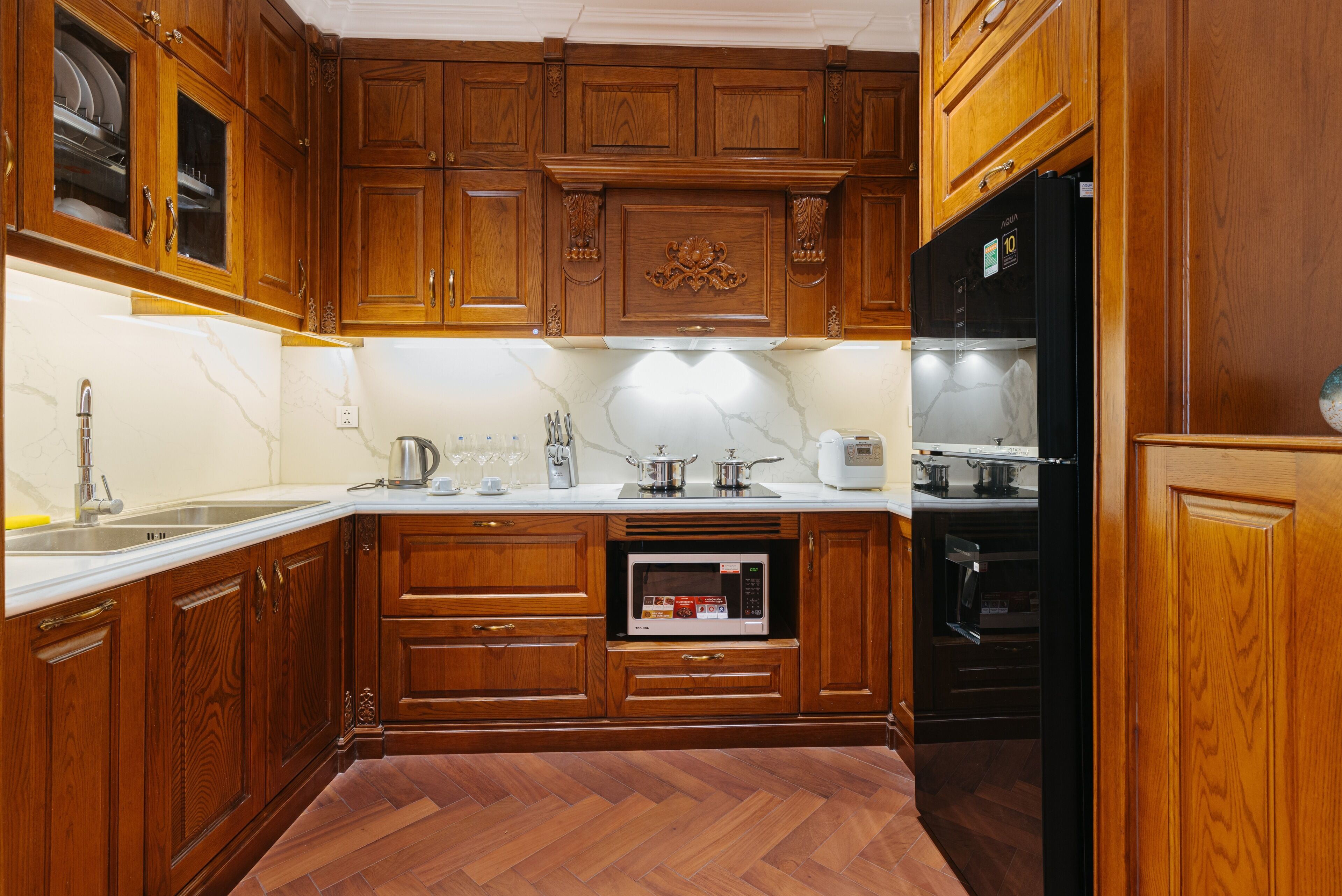Een keuken met houten kastjes, een magnetron, een oven en een spoelbak.