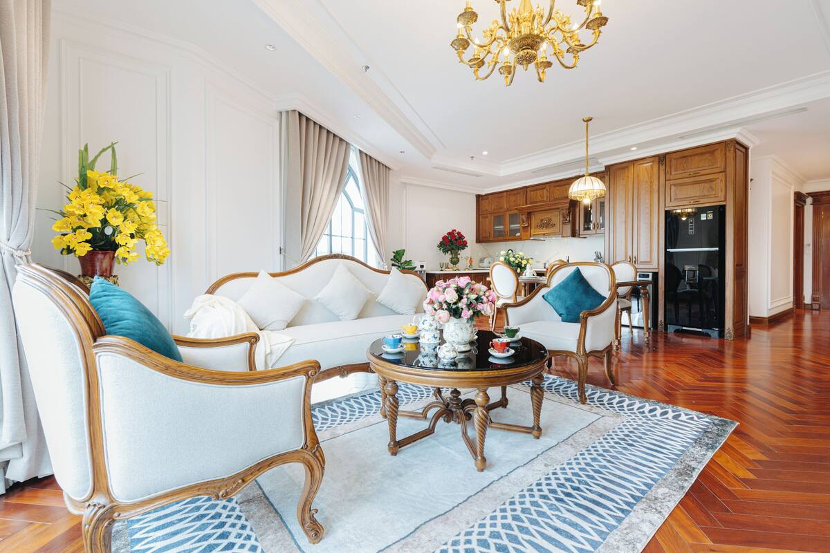 Un salon spacieux comprenant un canapé, des fauteuils, une table basse et un lustre.