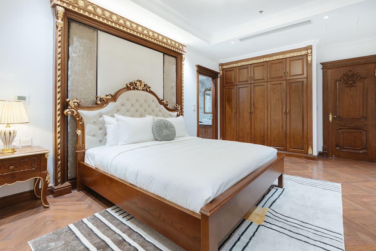 Une chambre à coucher avec un grand lit, une armoire en bois et un miroir.