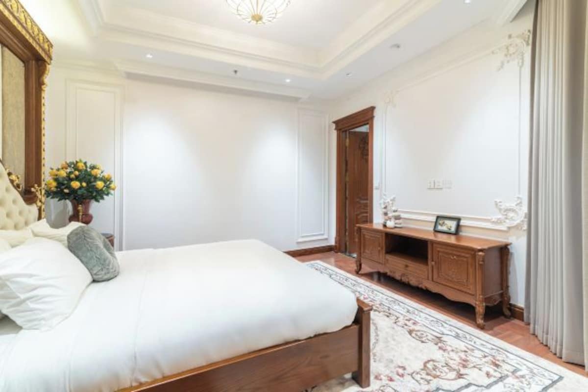 Quarto com uma cama grande, penteadeira de madeira e espelho.