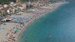 A coastal town with a long sandy beach lined with umbrellas and beachgoers. - B&B Romeo e Giulietta Scilla (Scilla)