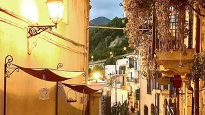 A narrow cobblestone street with outdoor seating, a wooden barrel, and a building with a balcony. - B&B Romeo e Giulietta Scilla (Scilla)