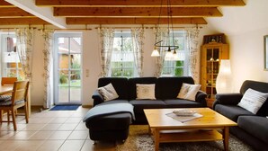 A cozy living room with a sofa set, a coffee table, and a cabinet. - Hier Finden Sie Ruhe und Erholung in Einem Gemütlichen und Komfortablen Friesenhaus an der Nordseeküste Ostfrieslands am Weltnaturerbe Wattenmeer (Nessmersiel)