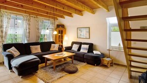 A cozy living room with a wooden ceiling, two sofas, a coffee table, and a small side table. - Hier Finden Sie Ruhe und Erholung in Einem Gemütlichen und Komfortablen Friesenhaus an der Nordseeküste Ostfrieslands am Weltnaturerbe Wattenmeer (Nessmersiel)