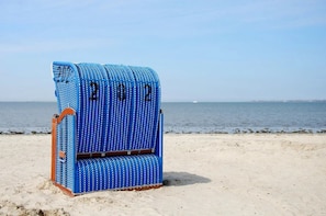 A blue beach chair with the numbers 2022 on it, placed on a sandy beach with the sea in the background.