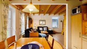 A cozy room with a wooden ceiling, a dining table with chairs, a sofa, and a television. - Hier Finden Sie Ruhe und Erholung in Einem Gemütlichen und Komfortablen Friesenhaus an der Nordseeküste Ostfrieslands am Weltnaturerbe Wattenmeer (Nessmersiel)