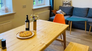 Una sala acogedora con una mesa de comedor de madera, un sofá y una ventana con cortinas.