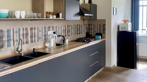 Una cocina moderna con estufa integrada, lavamanos y un refrigerador negro.